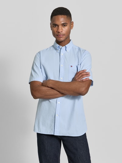 Männermodel trägt Regular Fit Freizeithemd aus reiner Baumwolle von Tommy Hilfiger, hellblau, uni, Button-Down, Ganzkörperansicht von vorne.