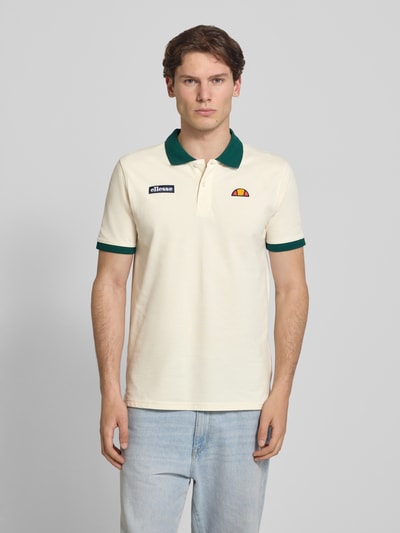 Männermodel trägt Regular Fit Poloshirt mit Label-Stitchings von ellesse in Creme mit grünem Kragen, Reine Baumwolle, Knopfleiste, Rückenlänge bei Größe M 77 cm, Ganzkörperansicht von vorne.