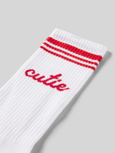 Produktfoto, Socken aus Baumwoll-Mix Modell 'Cutie' von Happy Socks, weiß mit roten Streifen und Label-Detail, strukturierte Rippenoptik.