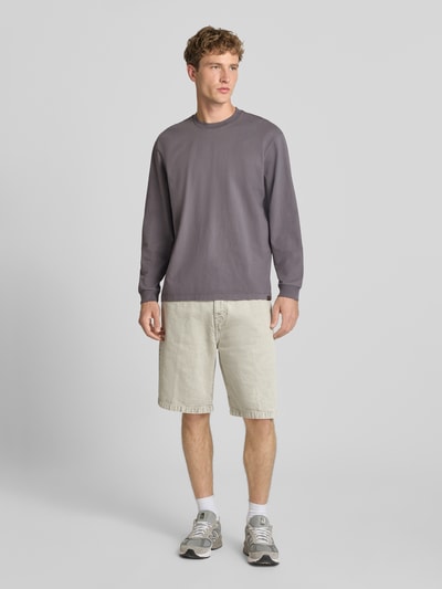 Männermodel trägt Loose Fit Langarmshirt aus reiner Baumwolle von Levi's®, Grau, kombiniert mit beigefarbenen Shorts, Ganzkörperansicht von vorne.