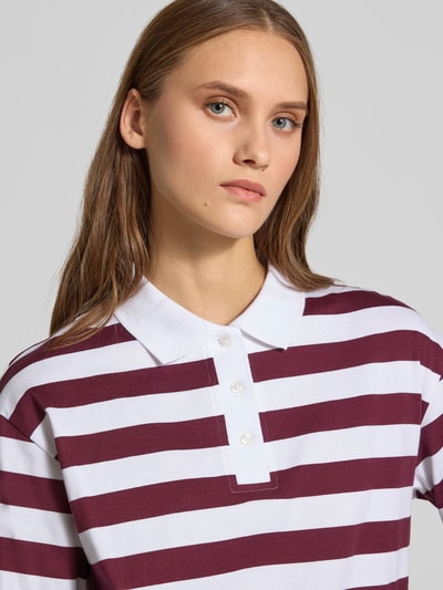 Frauenmodel trägt Relaxed Fit Poloshirt aus reiner Baumwolle Modell 'Dollie' von NOISY MAY® mit breiten bordeaux-weißen Streifen, Nahaufnahme Oberkörper.