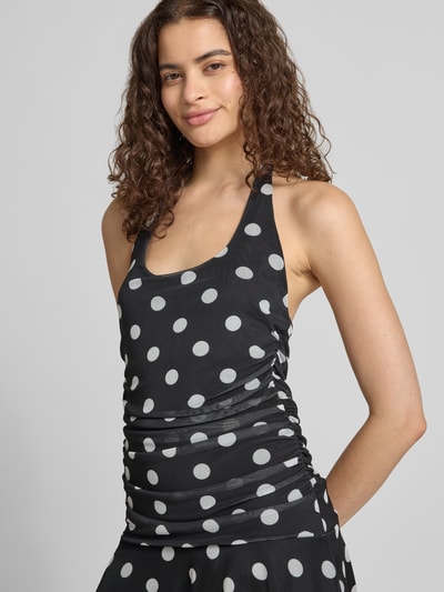 Frauenmodel trägt Neckholder-Minikleid im Allover-Look Modell 'DOTTIE' von NOISY MAY®, Slim Fit, schwarz mit weißen Punkten, Nahaufnahme Oberkörper.