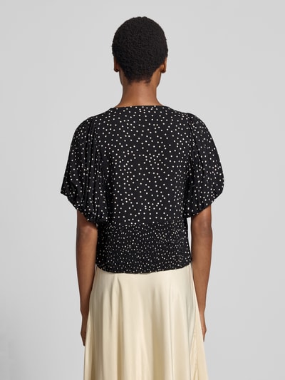Vrouwenmodel draagt blouse met korte mouwen van zuiver viscose Model 'GILDA' van Soyaconcept, slim fit, v-hals, pofmouwen, ruglengte maat S 33 cm, mouwlengte maat S 27 cm, zwarte stof met witte stippen, gladde textuur, geheel van achteren
