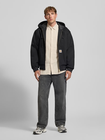 Männermodel trägt Regular Fit Freizeithemd aus reiner Baumwolle von G-Star RAW in Beige, kombiniert mit dunkler Jacke und Jeans, Ganzkörperansicht von vorne.