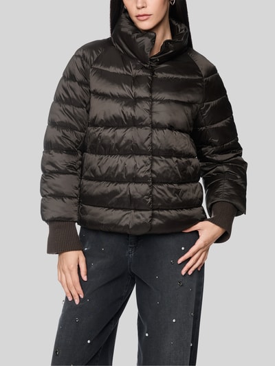 Frauenmodel trägt Steppjacke mit Stehkragen und Label-Detail von Marc Cain in Dunkelbraun, glänzende Oberfläche, Nahaufnahme Oberkörper. Rückenlänge, Schulterbreite, Brustweite und Ärmellänge bei Größe 36 gemäß Kontext.