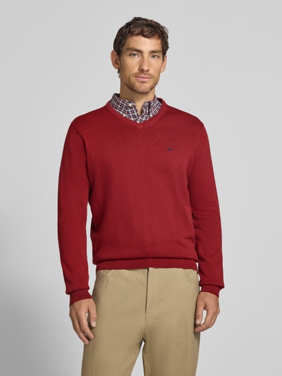 Männermodel trägt Strickpullover mit Label-Strickerei von Fynch-Hatton in Rot, reine Baumwolle, gerader Schnitt, V-Ausschnitt, Ganzkörperansicht von vorne.