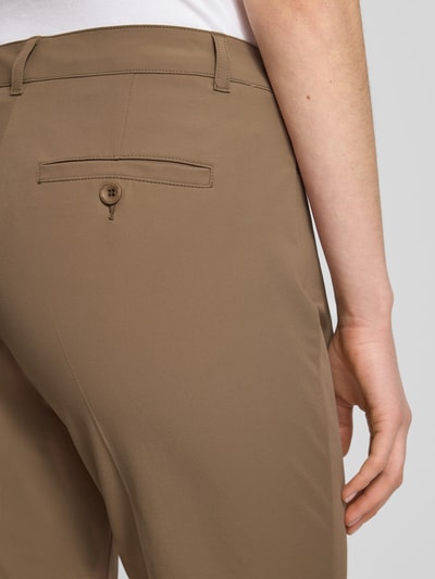 Frauenmodel trägt Chino aus Techno Cotton Superstretch Modell 'UTE' von Raffaello Rossi in Beige, Elastischer-Material-Mix, Detailaufnahme Rückansicht, Eingriffstaschen, Gesäßtasche mit Knopf, fixierte Beinumschläge, Bügelfalten, Gürtelschlaufen, Straight Fit, Verkürzte Passform, Knopf- und Reißverschluss, glatte Textur, Bundweite 40 cm, Innenbeinlänge 68 cm bei Größe 36.