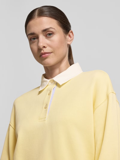 Frauenmodel trägt Longsleeve mit Polokragen und kurzer Knopfleiste von Gant in Gelb aus Baumwoll-Mix, Loose-Fit, Nahaufnahme Oberkörper.