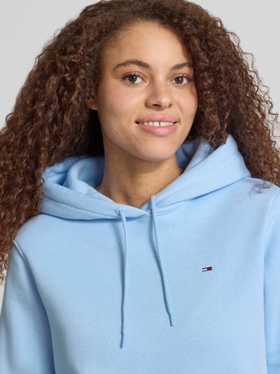 Frauenmodel trägt Regular Fit Hoodie aus Baumwoll-Mix von Tommy Jeans in Optik: Unifarben mit Logo-Stitching, Nahaufnahme Oberkörper.