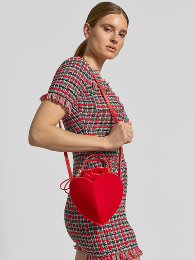 Modelka nosi czerwoną Henkeltasche mit Herzform Modell 'D-TASCHE' od Rotate z aksamitnej bawełny, jednolita, z połyskiem, widok całej sylwetki z przodu.
