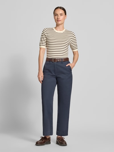 Frauenmodel trägt Slim Fit Pullover aus Viskose-Mix von s.Oliver RED LABEL in Beige mit schwarzen Streifen, kombiniert mit blauer Hose, Ganzkörperansicht von vorne.