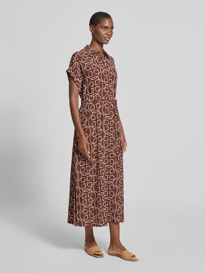 Frauenmodel trägt Midikleid aus Viskose mit Bindegürtel von Gant in Braun mit Weiß, Taillierter Schnitt, Hemdblusenkragen, abstraktes Muster, verdeckte Knopfleiste, Rückenlänge bei Größe 36: 130 cm, Brustweite: 53 cm, Ärmellänge: 10 cm, Ganzkörperansicht von vorne.