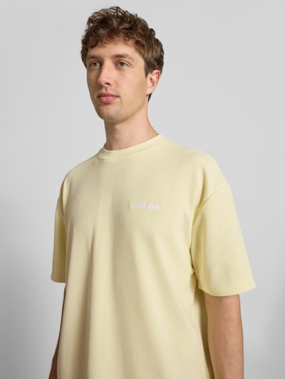Męski model nosi Oversized T-Shirt mit Logo-Stitching Modell 'Lagos' od Pegador, elastyczna mieszanka materiałów, krój oversized fit, długość tyłu w rozmiarze M: 65 cm, jasny żółty kolor, gładka struktura, Nahaufnahme Oberkörper.