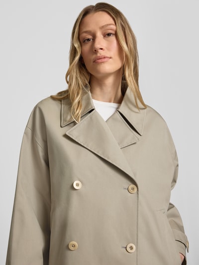 Frauenmodel trägt Trenchjacke mit Reverskragen Modell 'HEATHER' von G-LAB, sandfarben, Knopfverschluss, Ärmelriegel, Nahaufnahme Oberkörper.