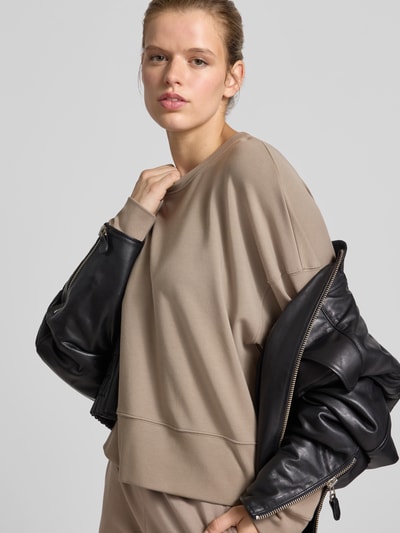 Frauenmodel trägt Oversized Sweatshirt mit breitem Bund von Juvia aus elastischem Baumwoll-Modal-Mix in Beige, Nahaufnahme Oberkörper.