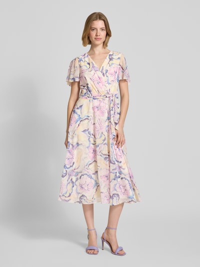 Frauenmodel trägt Midikleid mit floralem Allover-Print von Christian Berg Cocktail in Pastellfarben, V-Ausschnitt, tailliert, Ganzkörperansicht von vorne.