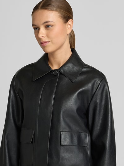 Frauenmodel trägt Jacke in Leder-Optik Modell 'SABINA' von Mango, Regular Fit, Hemdblusenkragen, schwarze Farbe, Nahaufnahme Oberkörper.