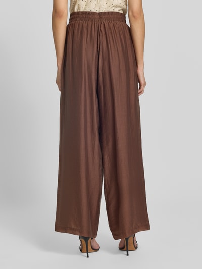 Frauenmodel trägt Regular Fit Weite Hose aus Lyocell-Mix von s.Oliver BLACK LABEL in Braun mit leichter Struktur, Ganzkörperansicht Rückansicht.