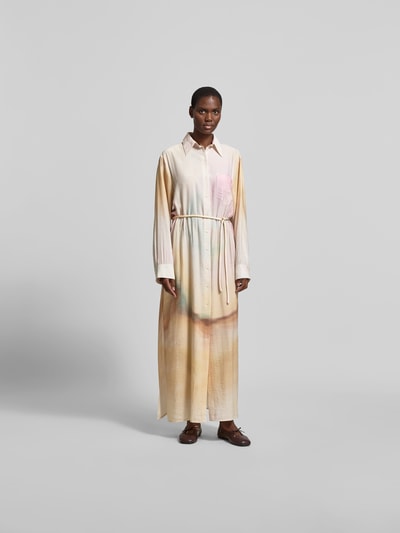 Frauenmodel trägt Hemdblusenkleid aus Viskose-Mix von Nanushka, Gerade Passform, durchgehende Knopfleiste, Hemdblusenkragen, langärmelig, Creme-Töne mit sanften Farbverläufen, glatte Textur, Gesamtlänge 134 cm, Brustweite 47 cm, Ärmellänge 64 cm, Ganzkörperansicht von vorne.