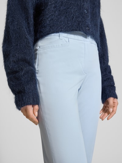 Frauenmodel trägt Chino aus Techno Cotton Superstretch Modell 'UTE' von Raffaello Rossi, Elastischer-Material-Mix, Straight Fit, verkürzt, Eingrifftaschen, Bügelfalten, Gürtelschlaufen, Produktdetails sichtbar, Nahaufnahme Oberkörper.
