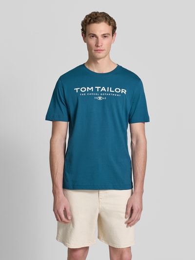 Męski model nosi Regular Fit T-Shirt aus reiner Baumwolle von Tom Tailor w jednolitym kolorze, nadruk z logo, krój regular fit, dekolt:, krótki rękaw, dżersej, czysta bawełna, widok całej sylwetki z przodu