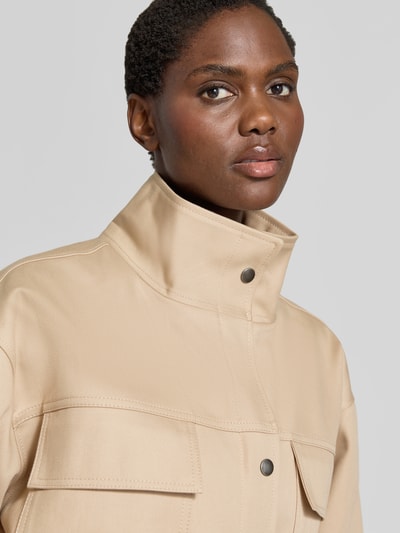 Frauenmodel trägt Funktionsjacke mit Taillengürtel Modell 'ODIN' von Anine Bing in Beige, matte Optik, Webware, Nahaufnahme Oberkörper.