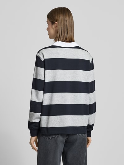 Frauenmodel trägt Polo-Langarmshirt mit Streifen und kontrastiger Knopfleiste von Review, reine Baumwolle, Regular Fit, Rückansicht.