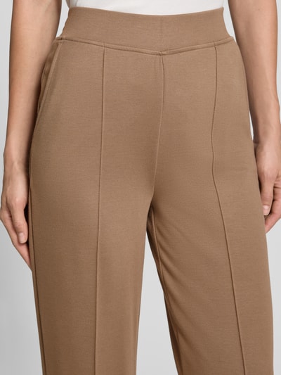 Vrouwenmodel draagt Straight Fit broek uit viscosemix van Milano Italy in beige met siernaad en elastische band, detailopname taille. Context: dames broek van Milano Italy, elastische viscosemix, straight fit, elastische band, siernaad, bandwijdte bij maat S: 36 cm, binnenbeenlengte bij maat S: 89 cm.