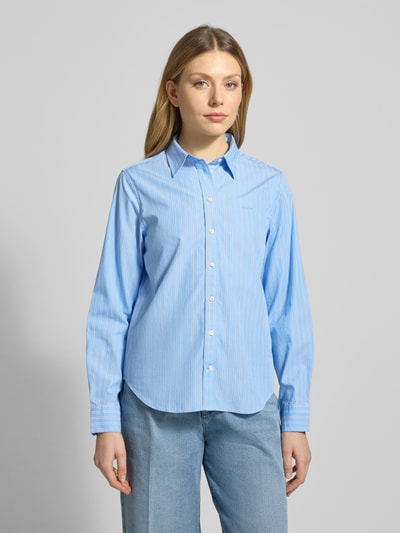 Vrouwenmodel draagt Regular fit blouse met labelstitching model 'ONEBUY' van Gant, puur katoen, overhemdkraag, knoopsluiting, lichtblauw met witte strepen. Ganzekijk van voren. Context: dames blouse, ruglengte maat 36: 65 cm, mouwlengte: 61 cm.