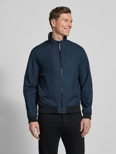 Männermodel trägt Regular Fit Jacke mit Stehkragen von MCNEAL in Dunkelblau mit Reißverschlüssen, elastischen Abschlüssen, Ganzkörperansicht von vorne.