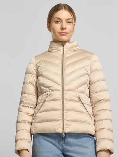 Frauenmodel trägt taillierte Steppjacke mit Zweiwege-Reißverschluss Modell 'ANYA' von Beaumont Amsterdam in Beige, strukturierte Oberfläche, Ganzkörperansicht von vorne. Die Jacke zeigt Kapuze mit Tunnelzug, gerade geschnittene Form, sichtbare Nahtdetails, Produktmaße Größe 36: Rückenlänge 55 cm, Schulterbreite 38 cm, Brustweite 48 cm, Ärmellänge 61 cm.