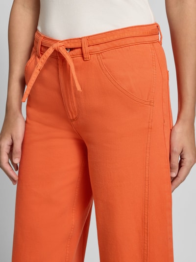 Vrouwenmodel draagt Jeans met Bindegordel van Jake*s Casual in feloranje, puur katoen, wide fit, met steekzakken, detailopname heup.