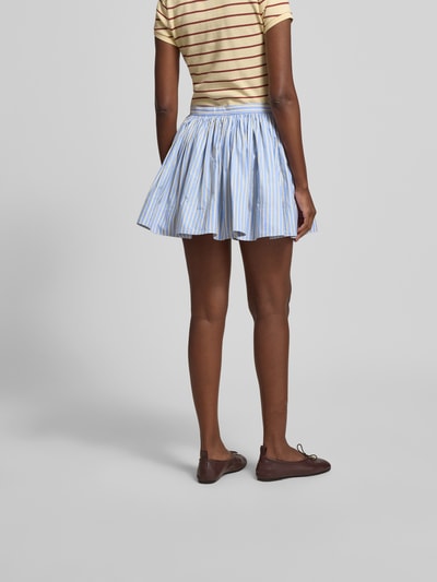 Frauenmodel trägt Minirock aus reiner Baumwolle von Rabanne mit A-Linie, Ziernähte, Label-Detail, blau-weiß gestreift, Minilänge, Ganzkörperansicht Rückansicht.