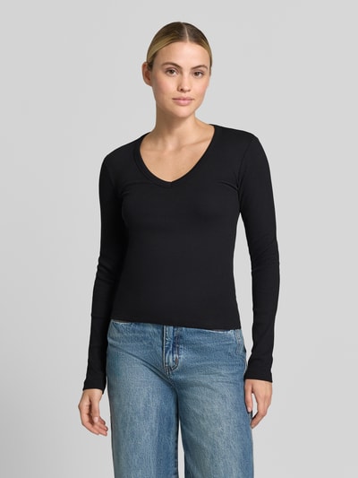 Frauenmodel trägt schwarzes Slim Fit Langarmshirt aus Baumwoll-Mix Modell 'CHLOE' von VERO MODA, kombiniert mit blauer Jeans, Ganzkörperansicht von vorne, Damen Langarmshirt von VERO MODA.