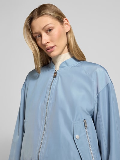 Kobiece model prezentuje Kurtka 'Jacke mit Reißverschlusstaschen' od Fuchs Schmitt, kolor błękitny, krój regular fit, stójka, zamek błyskawiczny, kieszenie zapinane na zamek błyskawiczny, długość tyłu w rozmiarze 36: 52 cm, szerokość ramion w rozmiarze 36: 54 cm, szerokość klatki piersiowej w rozmiarze 36: 57 cm, długość rękawów w rozmiarze 36: 53 cm, zbliżenie na górną część ciała.