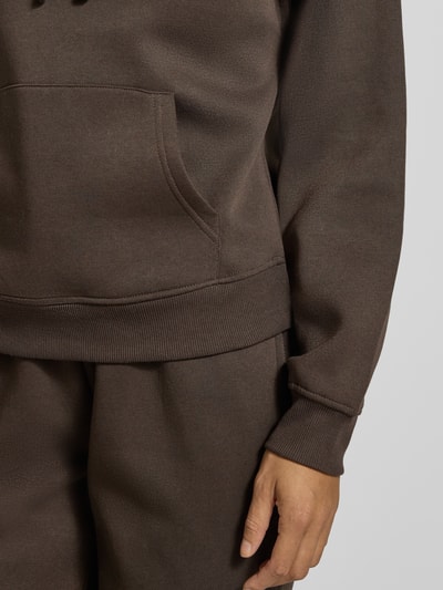 Frauenmodel trägt Regular Fit Hoodie aus Baumwoll-Mix Modell 'BEST' von ONLY in Dunkelbraun mit feiner Struktur, Nahaufnahme Oberkörper. Damen Hoodie von ONLY
