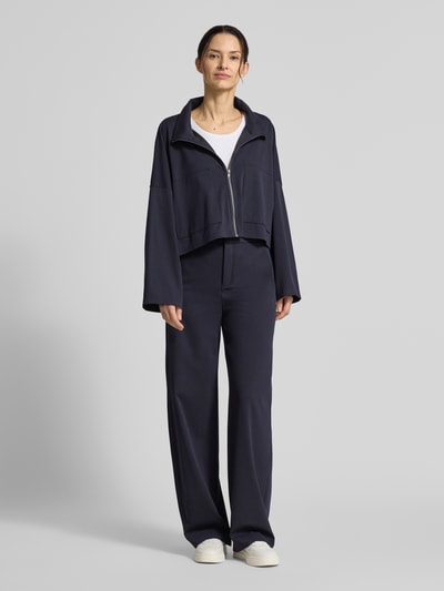 Vrouwenmodel draagt Relaxed Fit blazer met viscose van Drykorn, opstaande kraag, ritssluiting, opgestikte zakken, donkerblauw, model 'Elstow', elastische materiaalmix, ruglengte maat 36: 50 cm, borstwijdte 75 cm, mouwlengte 41 cm. Ganzkörperansicht van voren.