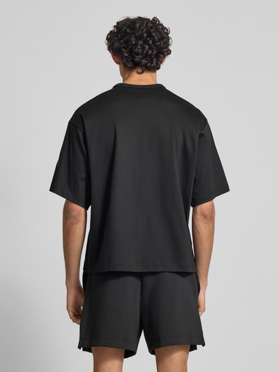 Männermodel trägt Relaxed Fit T-Shirt aus reiner Baumwolle von adidas Sportswear, Optik: Unifarben, Ganzkörperansicht Rückansicht.