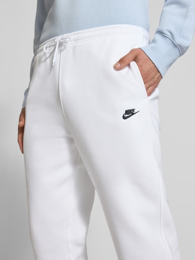 Männermodel trägt Sweatpants mit Label-Stitching und Gesäßtasche von Nike aus Baumwoll-Mix in Weiß, Regular-Fit, Nahaufnahme Oberkörper.