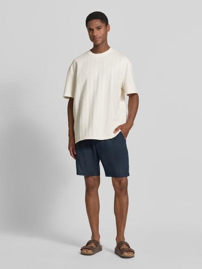 Männermodel trägt T-Shirt mit Strukturmuster und Rundhalsausschnitt von Les Deux, Material-Mix mit Viskose-Anteil, Regular-Fit, Herren T-Shirt, Rückenlänge bei Größe M 67 cm, helle Farbe, weiche Textur, Ganzkörperansicht von vorne.
