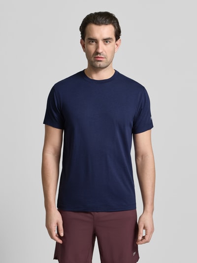 Męski model nosi Regular Fit T-Shirt mit Rundhalsausschnitt od Fabletics, bawełniany miks z dodatkiem modalu, krój regular fit, okrągły dekolt, krótki rękaw, długość tyłu w rozmiarze M: 70 cm, granatowa tkanina, jednolita faktura, pełny widok z przodu