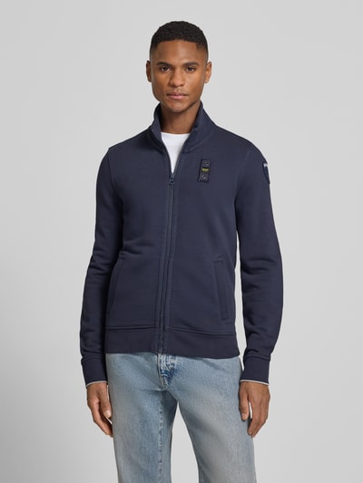 Männermodel trägt Sweatjacke mit Stehkragen Modell 'City New' von Blauer Usa, dunkelblau, Baumwoll-Mix, Slim-Fit, Label-Detail, Reißverschluss, Ganzkörperansicht von vorne. Rückenlänge bei Größe M: 45 cm, Ärmellänge: 84 cm.