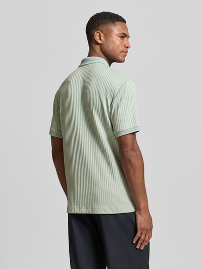 Männermodel trägt Regular Fit Poloshirt mit Baumwoll-Anteil Modell 'FAVE' von SELECTED HOMME, efekt: jednolity kolor, krój regular fit, kołnierzyk polo, zapięcie: krótki zamek błyskawiczny, rękaw: krótki rękaw, zakończenie rękawów: dzianinowy ściągacz, wykończenie materiału: prążkowana faktura. Ganzkörperansicht Rückansicht.