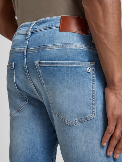 Männermodel trägt Slim Fit Jeans aus Baumwoll-Mix Modell 'DELAWARE' von BOSS Orange in Used Denim Optik, Nahaufnahme Rückansicht.