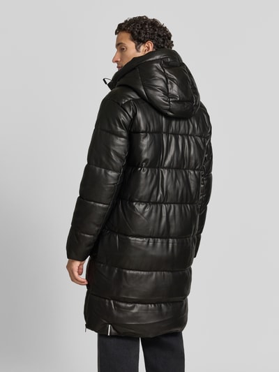 Männermodel trägt Regular Fit Mantel in Stepp-Optik Modell 'EMMET' von khujo, Kapuze, schwarze Farbe, Ganzkörperansicht Rückansicht.
