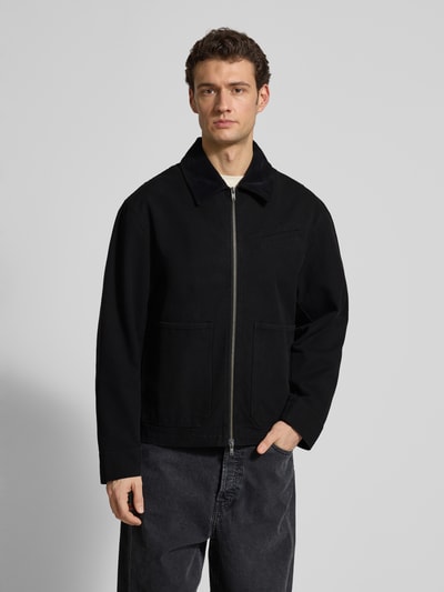 Männermodel trägt schwarze Jacke mit Zweiwege-Reißverschluss Modell 'Bo' von Wood Wood aus reiner Baumwolle, Ganzkörperansicht von vorne
