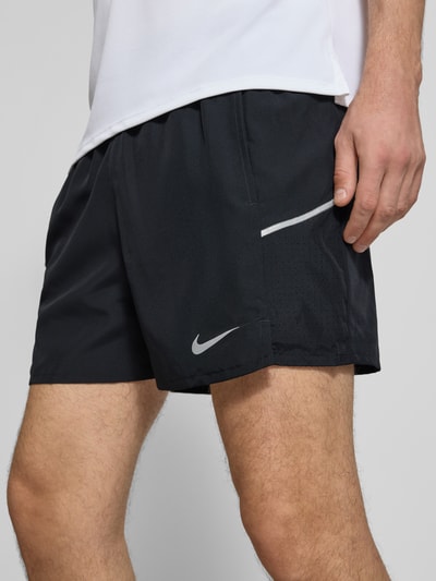 Männermodel trägt Shorts mit seitlichen Eingrifftaschen und Logo-Print von NIKE TRAINING in Schwarz, Loose-Fit, Nahaufnahme Oberschenkel.