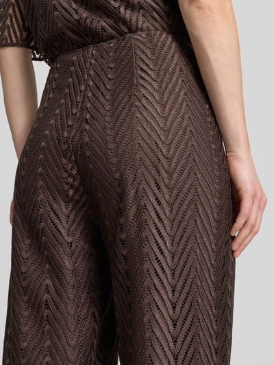 Frauenmodel trägt Hose aus Häkelspitze mit Innenfutter von comma in Braun, Textur mit Zickzackmuster, Nahaufnahme Rückansicht, weites Bein.