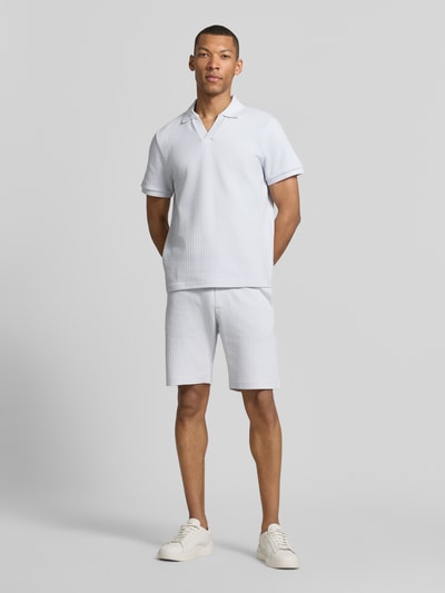 Männermodel trägt Regular Fit Strick-Poloshirt mit V-Ausschnitt von MCNEAL aus Baumwoll-Mix mit Stretch-Anteil, Ganzkörperansicht von vorne.