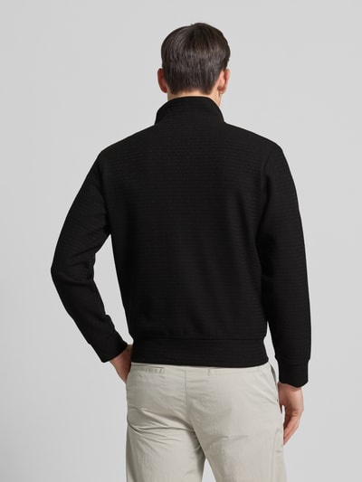 Männermodel trägt Sweatjacke mit Stehkragen von Emporio Armani in Schwarz, Baumwoll-Lyocell-Mix mit Stretch-Anteil, lockerer Schnitt, Rückenlänge 64 cm, gerippte Abschlüsse, Eingrifftaschen, Ganzkörperansicht Rückansicht.